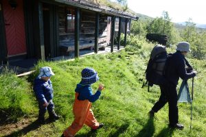 Mutter und Kinder bei einer Hütte, im Begriff, die Wanderung für diesen Tag zu beginnen.